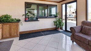 Um saguão de hotel com piso de azulejos, um armário de madeira, uma janela com vista e um sofá estampado.