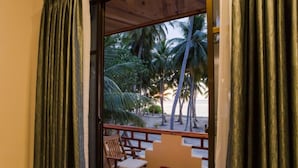 Una habitación con vista a palmeras y a la playa.