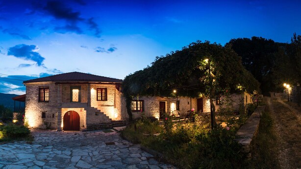 A stone house with a red door, a stone pathway, and a garden with flowers. - Rodami (North Tzoumerka)