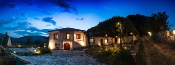 Una casa de piedra con puerta roja, un sendero de piedra y un jardín lleno de flores.