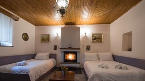 A cozy room with two beds, a fireplace, and a wooden ceiling. - Rodami (North Tzoumerka)