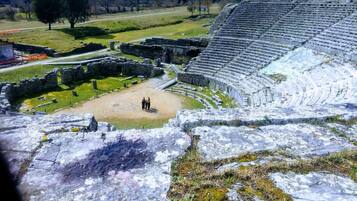 An ancient amphitheater with stone seating and a central stage area.