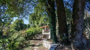 A stone pathway leading to a wooden pergola in a wooded area. - Rodami (North Tzoumerka)