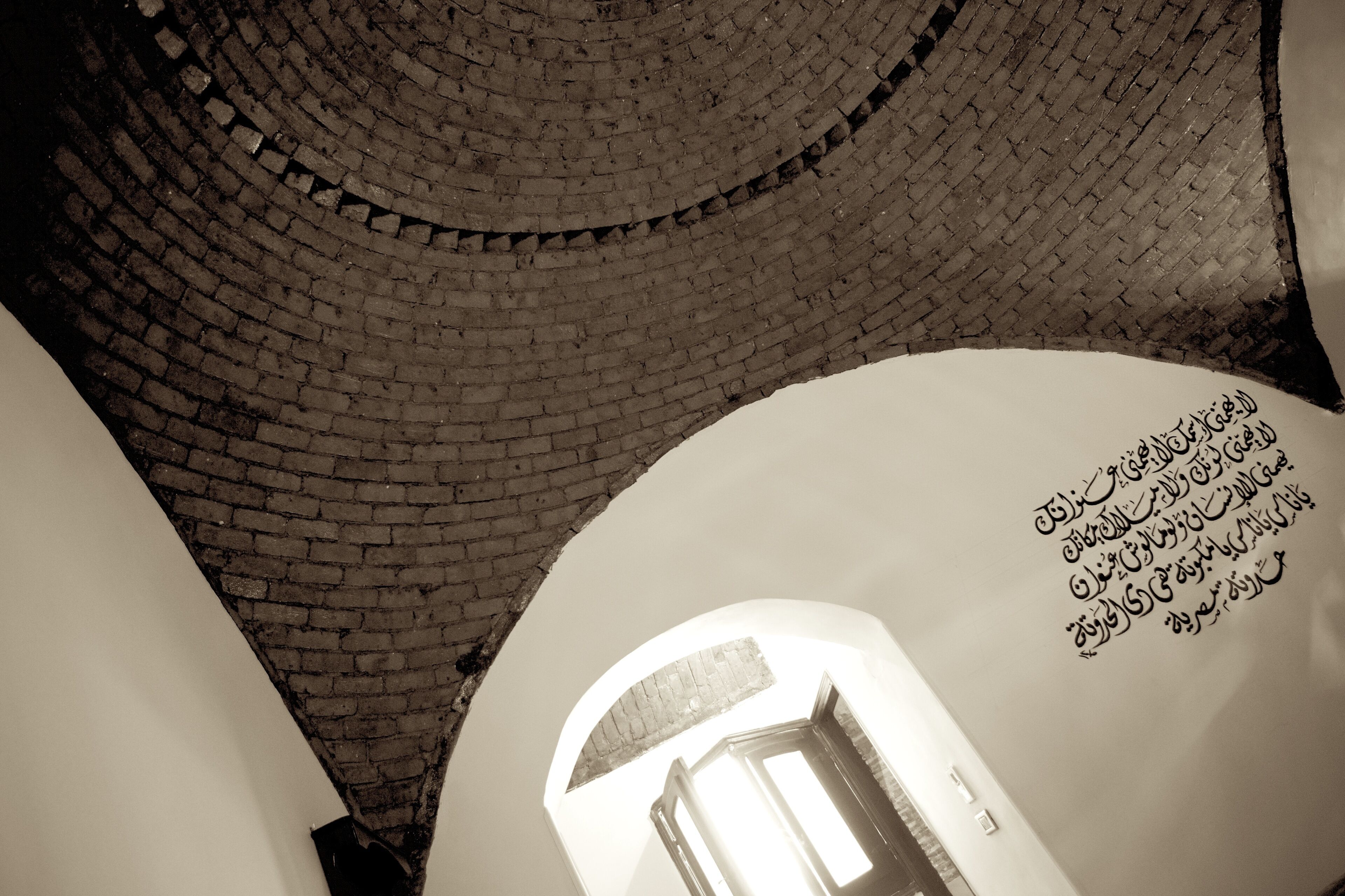A view of a brick spiral staircase leading upwards, with a door at the bottom.