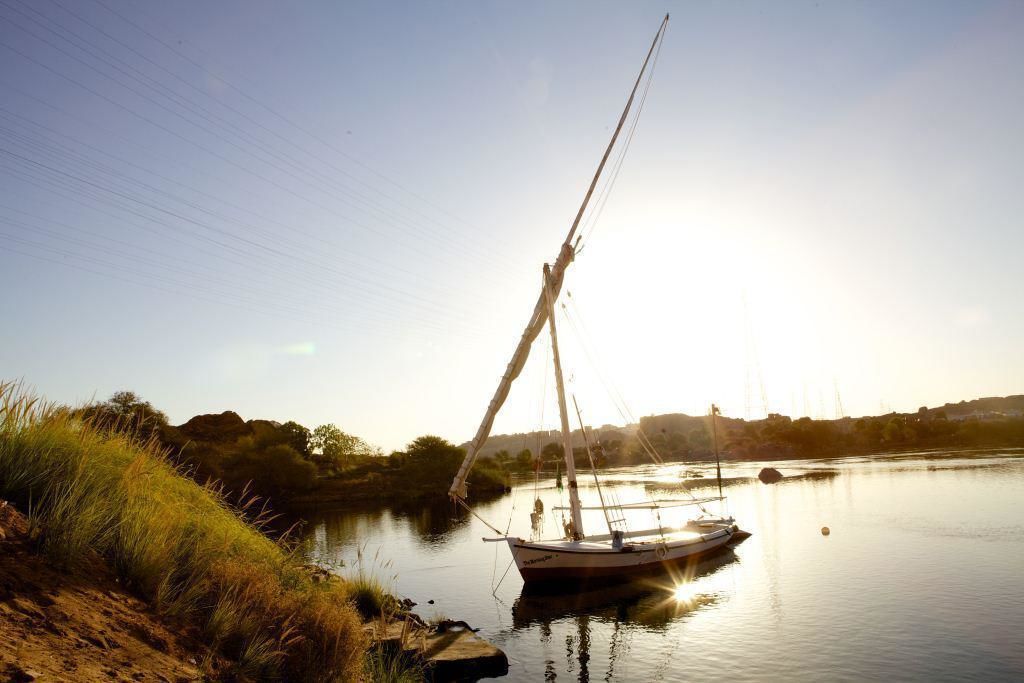 A sailboat docked at a calm riverbank with a clear sky.