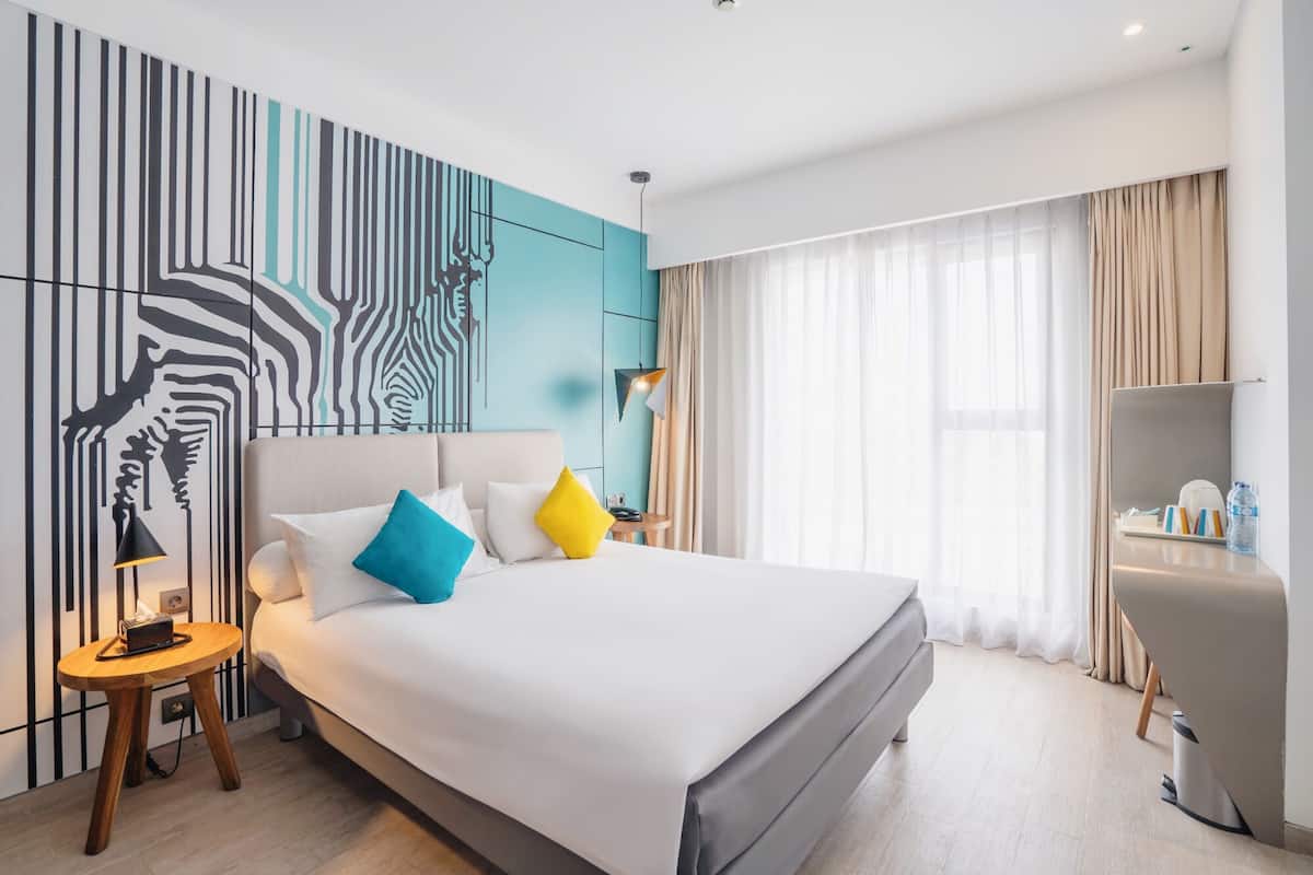 Ein modernes Hotelzimmer mit einem großen Bett, einem Schreibtisch und einer Wand mit Zepramuster.