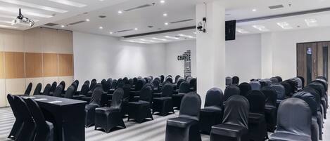 A conference room with rows of chairs, a projector, and a 'CHANGE' sign on the wall.
