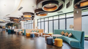 A spacious lobby with a modern design, featuring a large seating area with sofas and ottomans, a reception desk, and large windows providing natural light. - Kamaniiya Petitenget Seminyak (Keroboken Kelod)