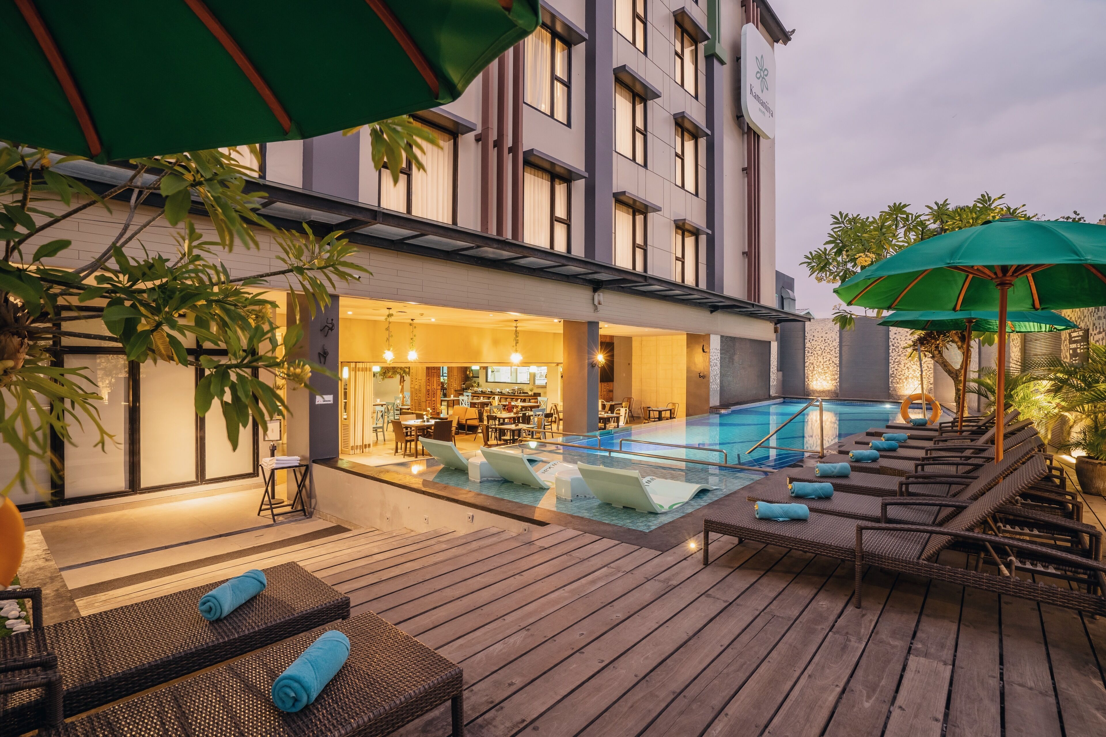 A rooftop pool area with lounge chairs and umbrellas, a bar area, and a building with a modern design.