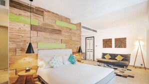 A modern bedroom with a large bed, a wooden accent wall, a sofa, and two wall art pieces. - Kamaniiya Petitenget Seminyak (Keroboken Kelod)