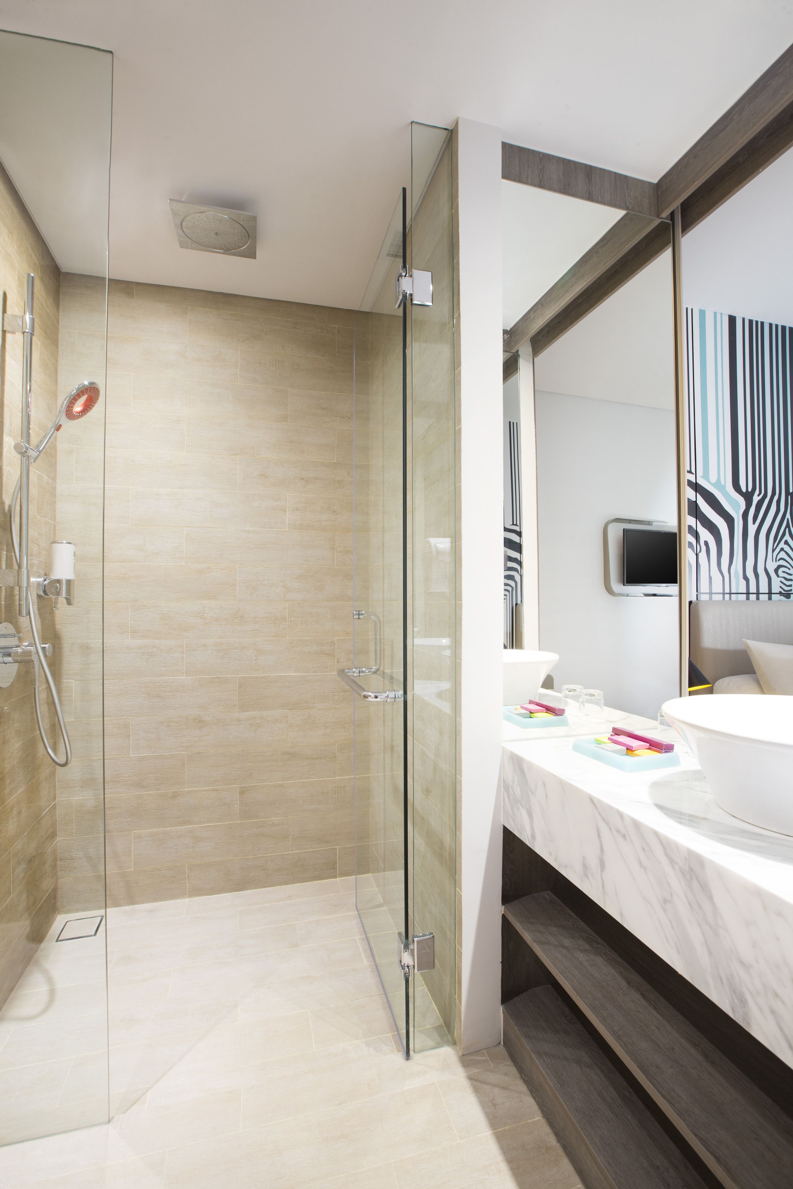 A modern bathroom with a glass shower enclosure, a marble countertop, and a large mirror.
