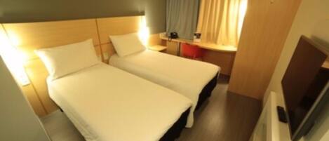 Een hotelkamer met twee bedden, een bureau en een televisie.