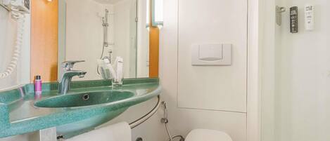 Un baño con un lavamanos verde, un inodoro blanco y una cabina de ducha con mampara de vidrio.