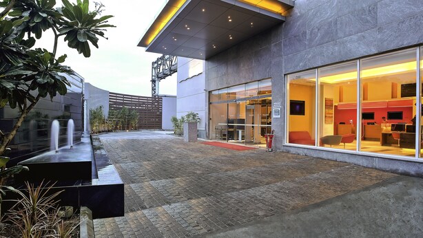 A modern building with a glass entrance, a water feature, and a paved courtyard.