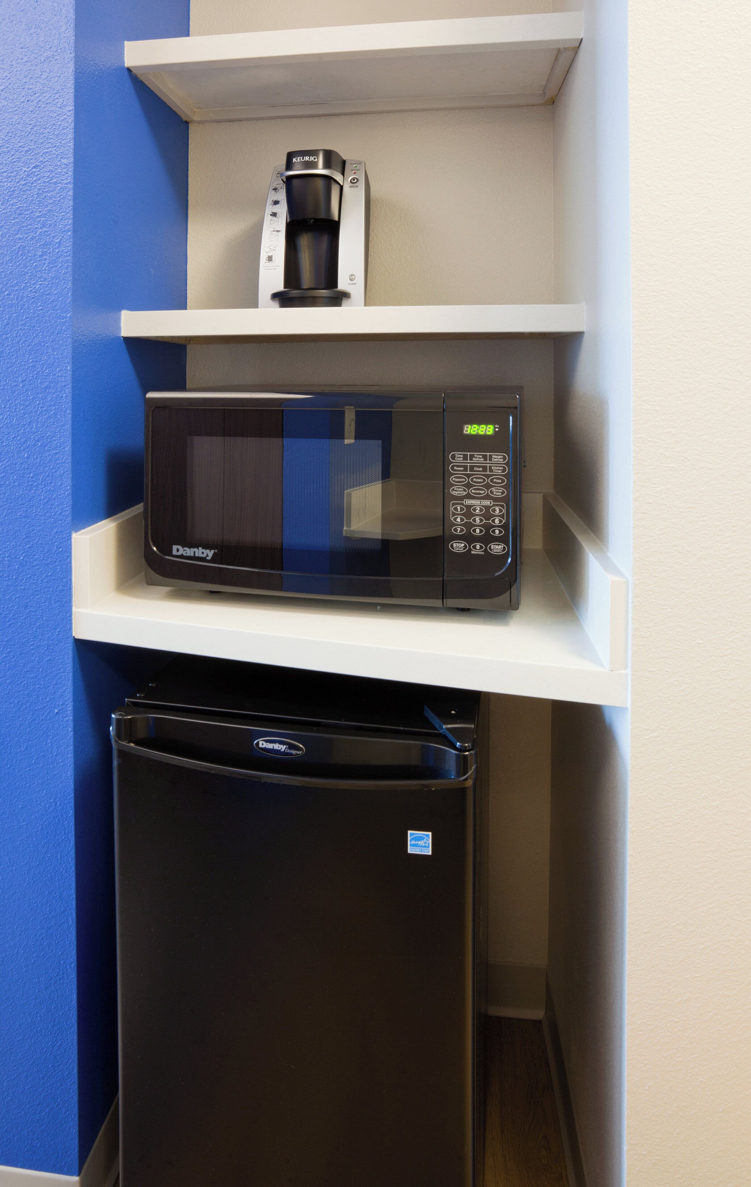 A compact kitchen setup with a microwave, coffee maker, and refrigerator.