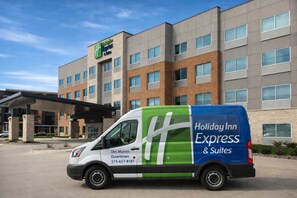 A Holiday Inn Express & Suites van parked in front of a hotel with a modern design, multiple floors, and a covered entrance. - Holiday Inn Express & Suites Des Moines Downtown by IHG (Des Moines)