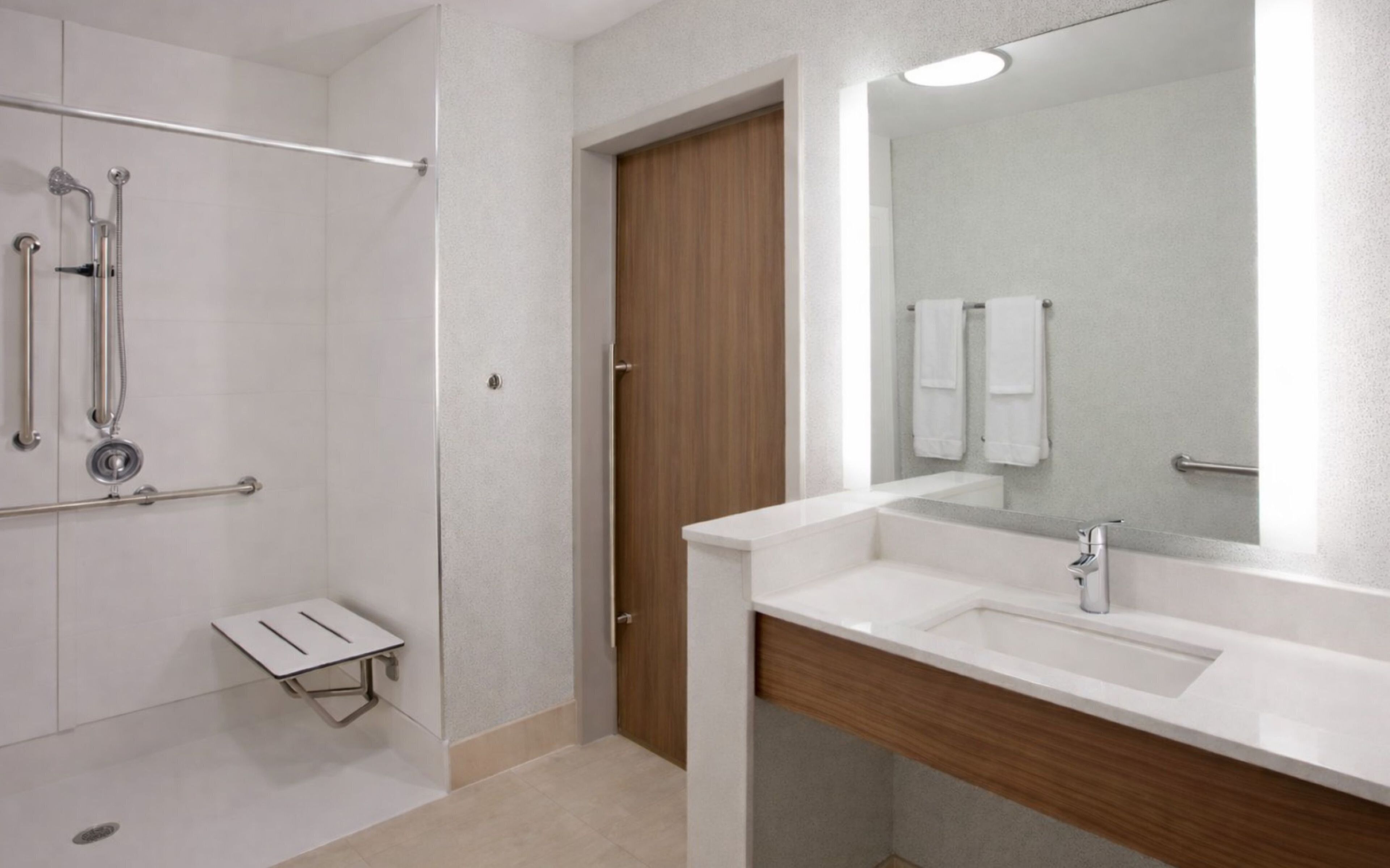 A modern bathroom with a shower, a vanity with a mirror, and a toilet.