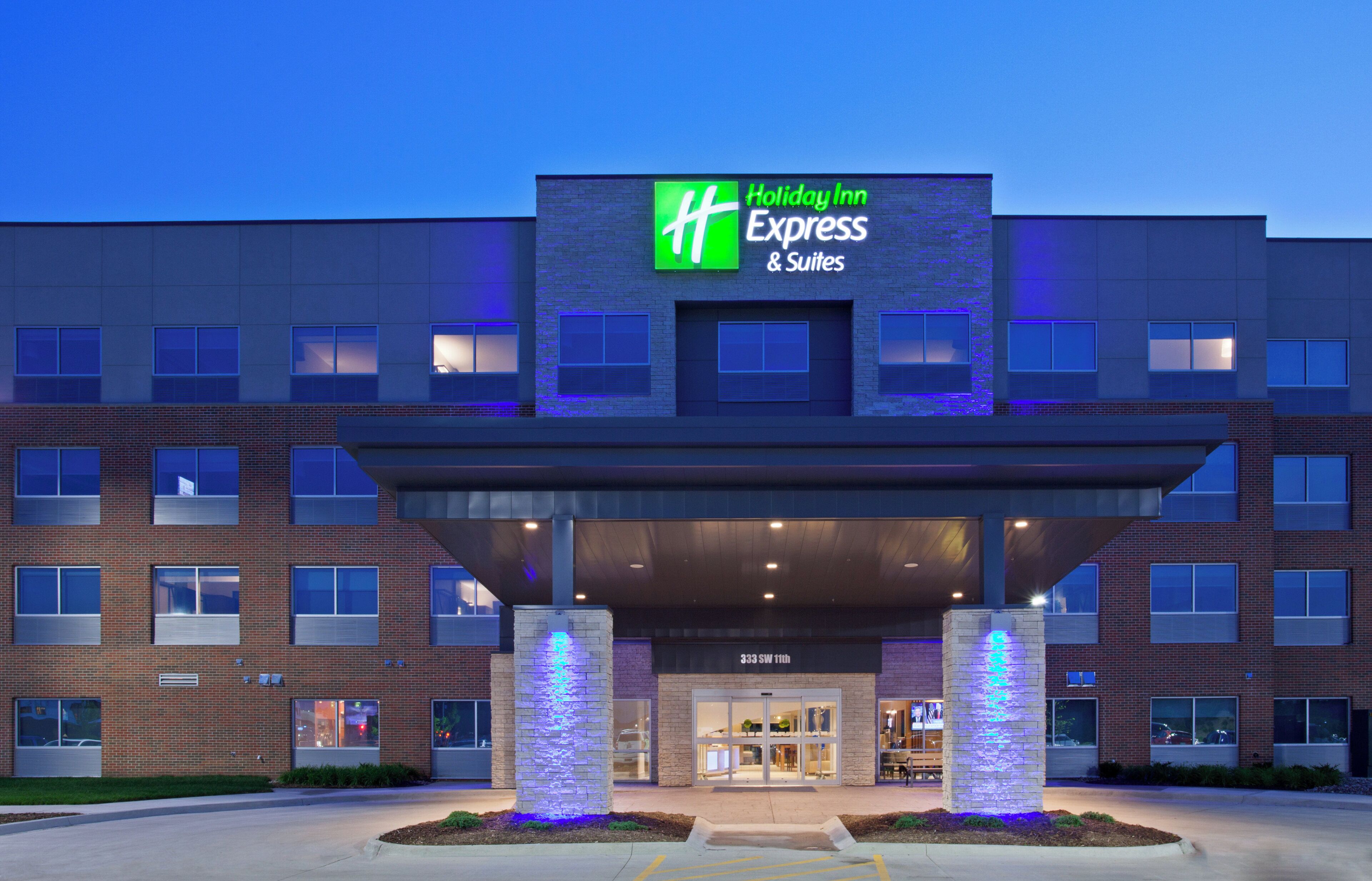 A Holiday Inn Express & Suites building with a brick facade, large windows, and a covered entrance area.