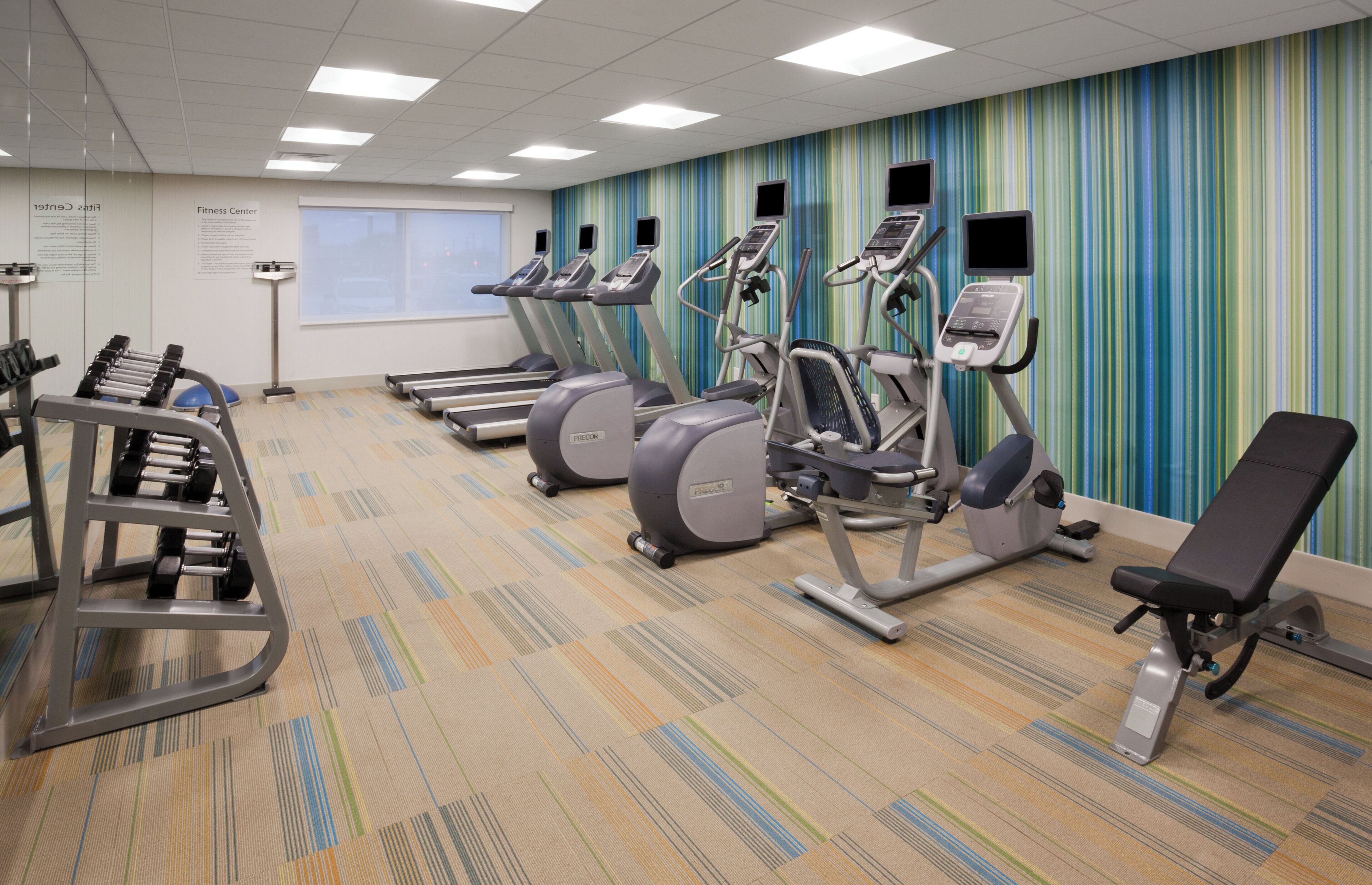 Ein Fitnessstudio mit Laufbändern, Crosstrainern und Gewichten.