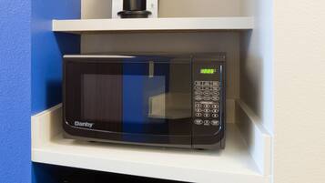 Un espace cuisine compact comprenant un four à micro-ondes, une machine à café et un réfrigérateur.