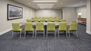 A conference room with a long table and green chairs, carpeted floor, and a framed cityscape picture on the wall. - Holiday Inn Express & Suites Clarion by IHG (Clarion)