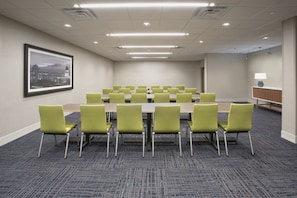 A conference room with a long table and green chairs, carpeted floor, and a framed cityscape picture on the wall. - Holiday Inn Express & Suites Clarion by IHG (Clarion)