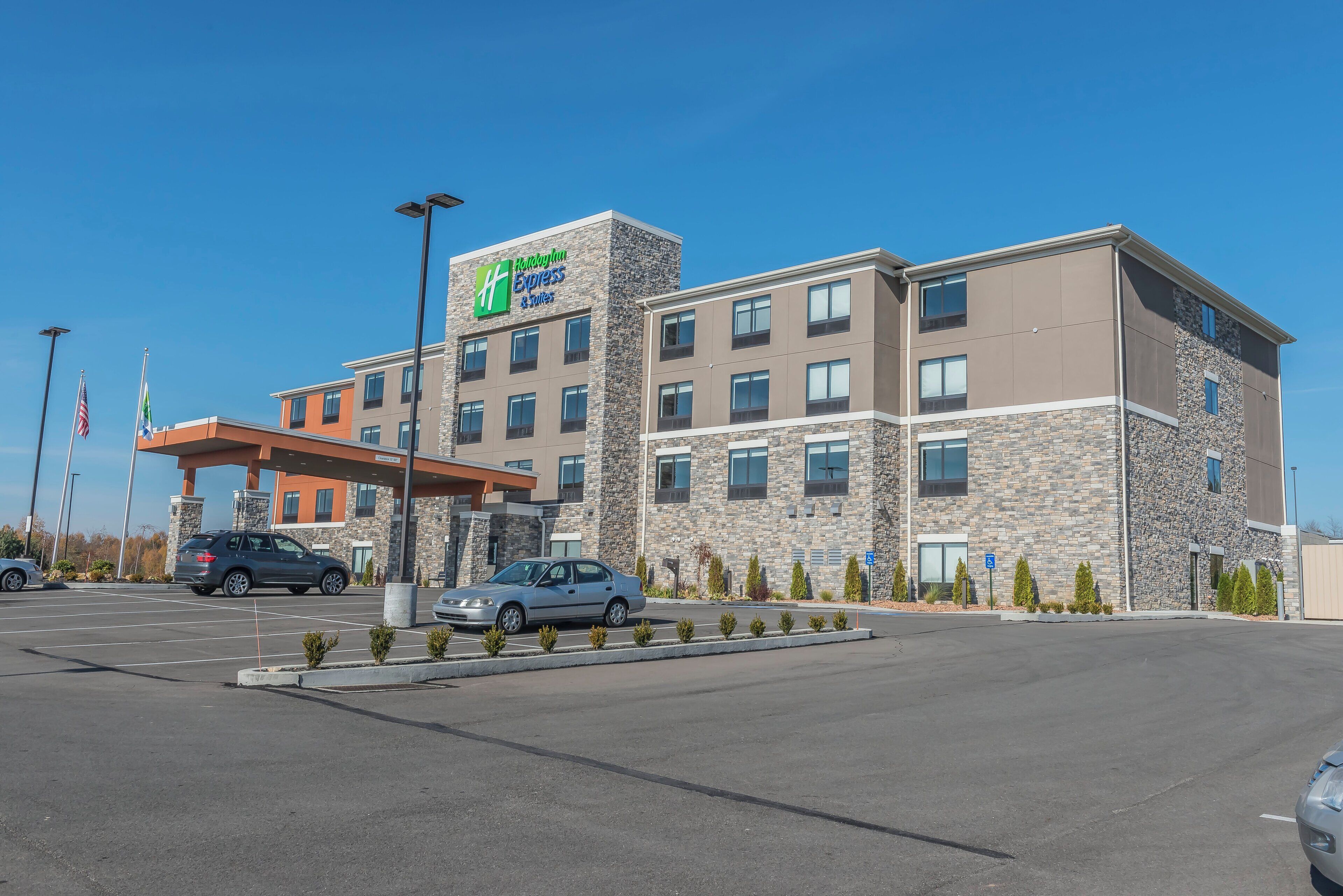 A Holiday Inn Express & Suites hotel with a stone facade, multiple windows, and a covered parking area.