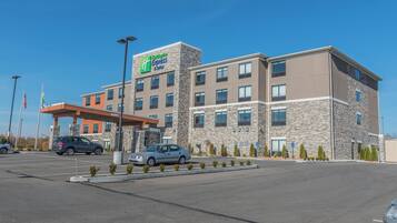 A Holiday Inn Express & Suites hotel with a stone facade, multiple windows, and a covered parking area.