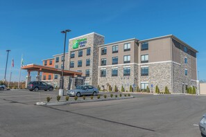 Holiday Inn Express & Suites -hotelli, jossa on kiviverhous, useita ikkunoita ja katettu pysäköintialue.