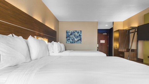 A hotel room with a large bed, a headboard, a wall-mounted artwork, and a television on the wall. - Holiday Inn Express & Suites Clarion by IHG (Clarion)