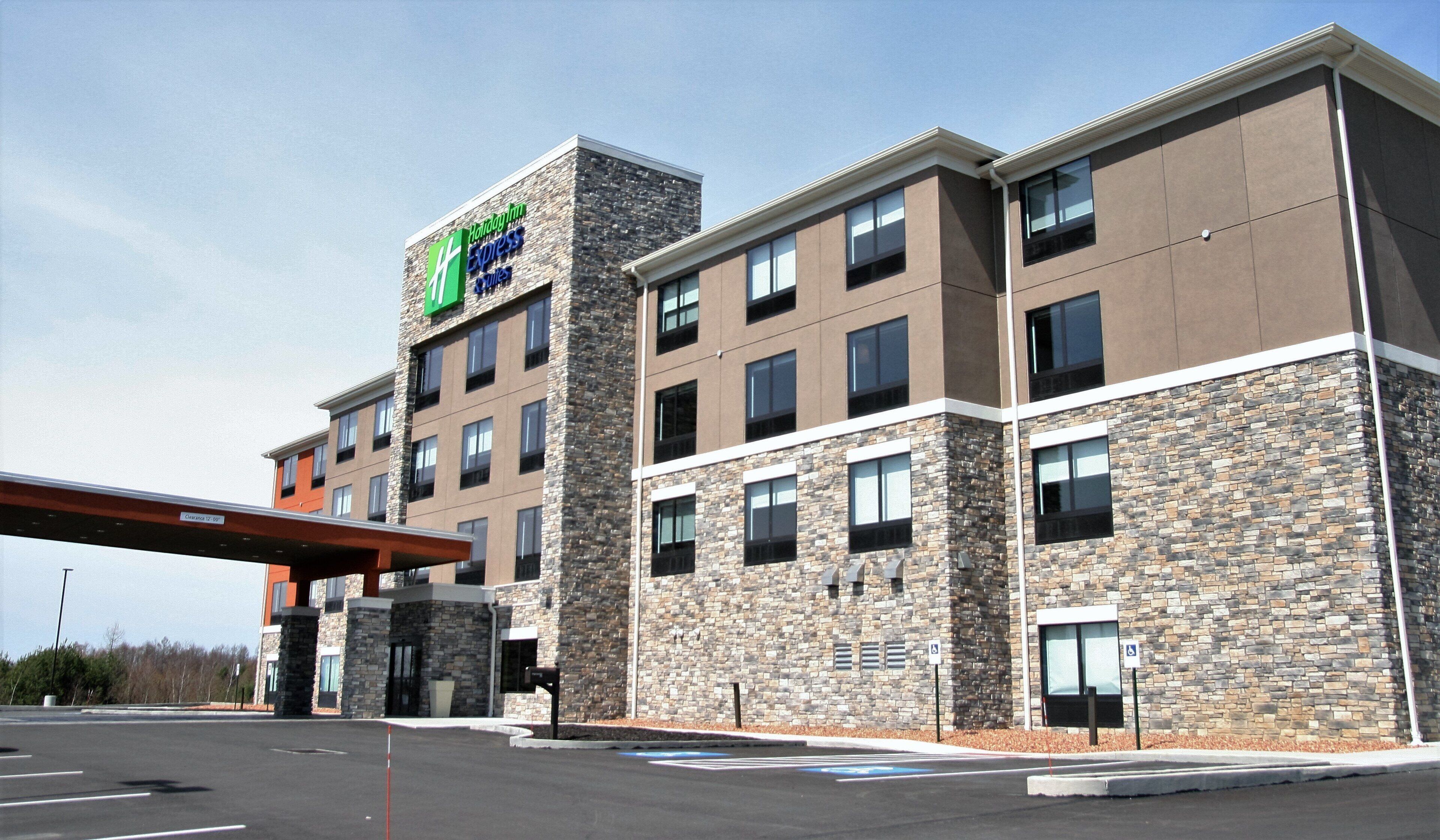 Un hôtel à la façade en pierre, avec plusieurs étages et une enseigne indiquant qu’il s’agit d’un Holiday Inn Express Suites.