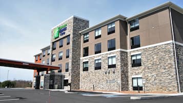 Un hôtel à la façade en pierre, avec plusieurs étages et une enseigne indiquant qu’il s’agit d’un Holiday Inn Express Suites.