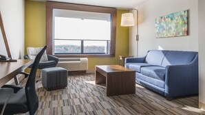 A modern living room with a blue sofa, a wooden coffee table, and a patterned rug. - Holiday Inn Express & Suites Clarion by IHG (Clarion)