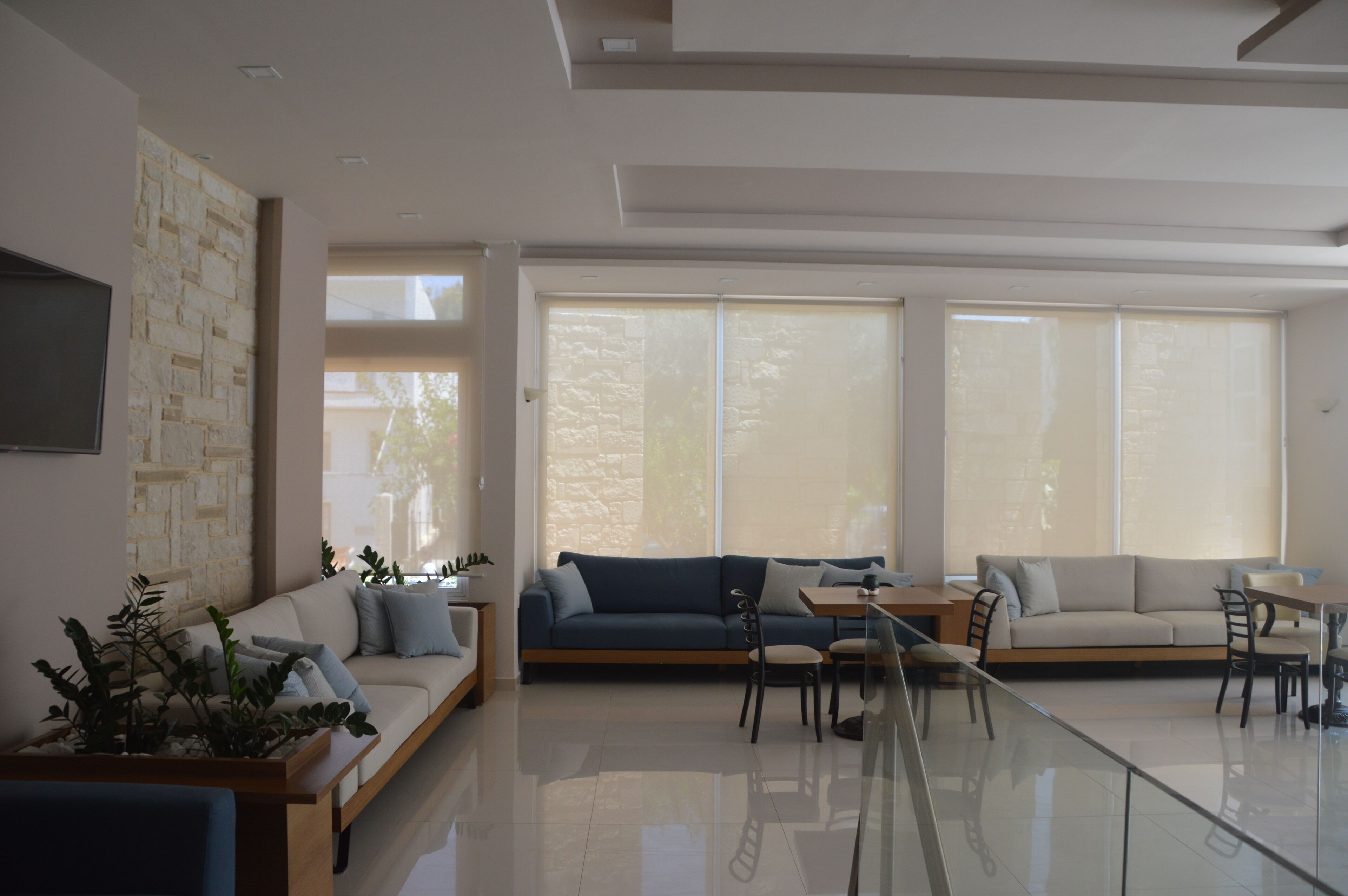 Una sala de estar moderna con sofá, sillones, una mesa de centro y televisor.