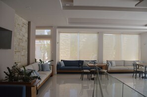 Una sala de estar moderna con sofá, sillones, una mesa de centro y televisor.