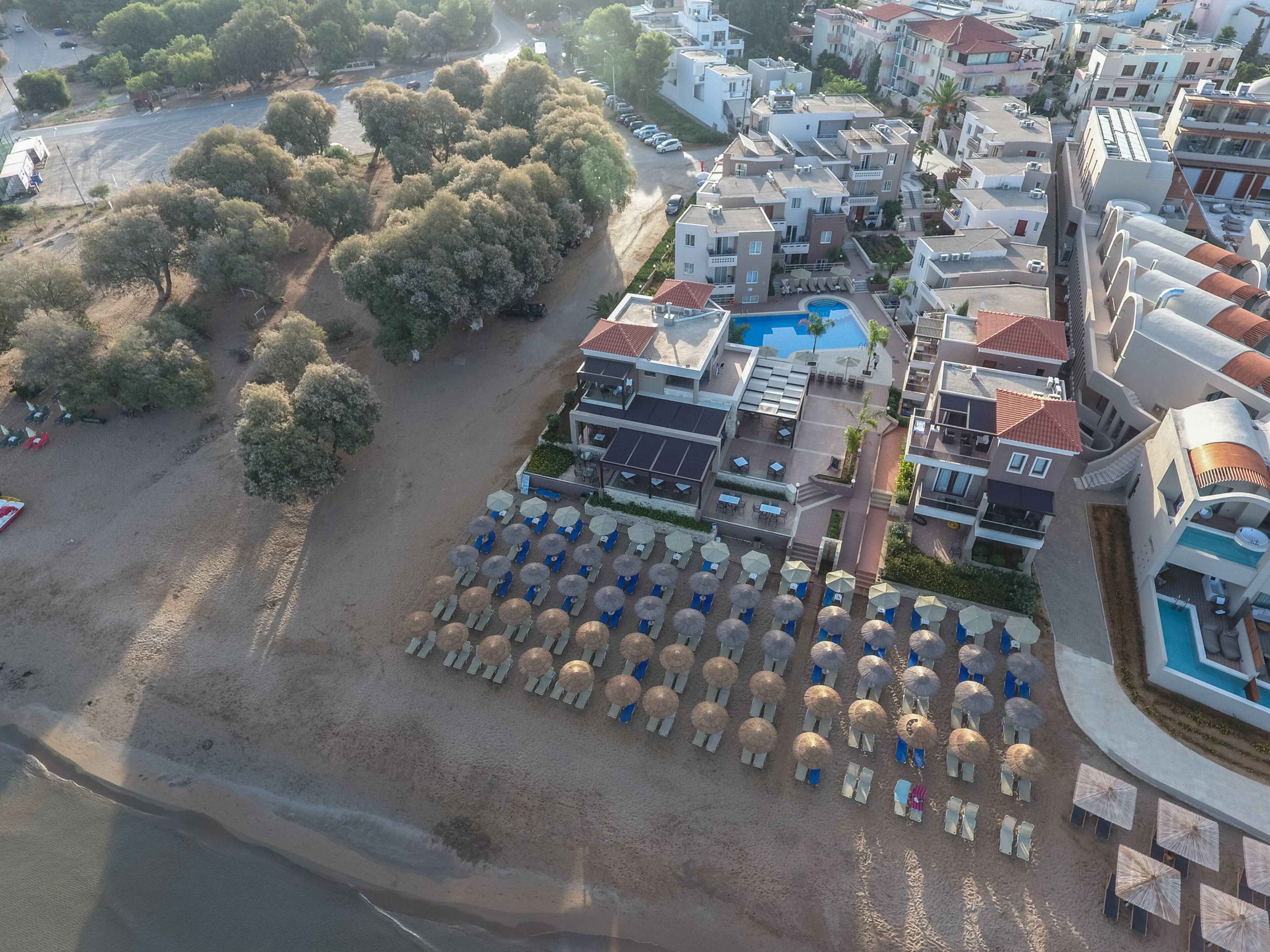 Vue aérienne d’un complexe hôtelier avec une piscine, des parasols de plage et une zone de plage.