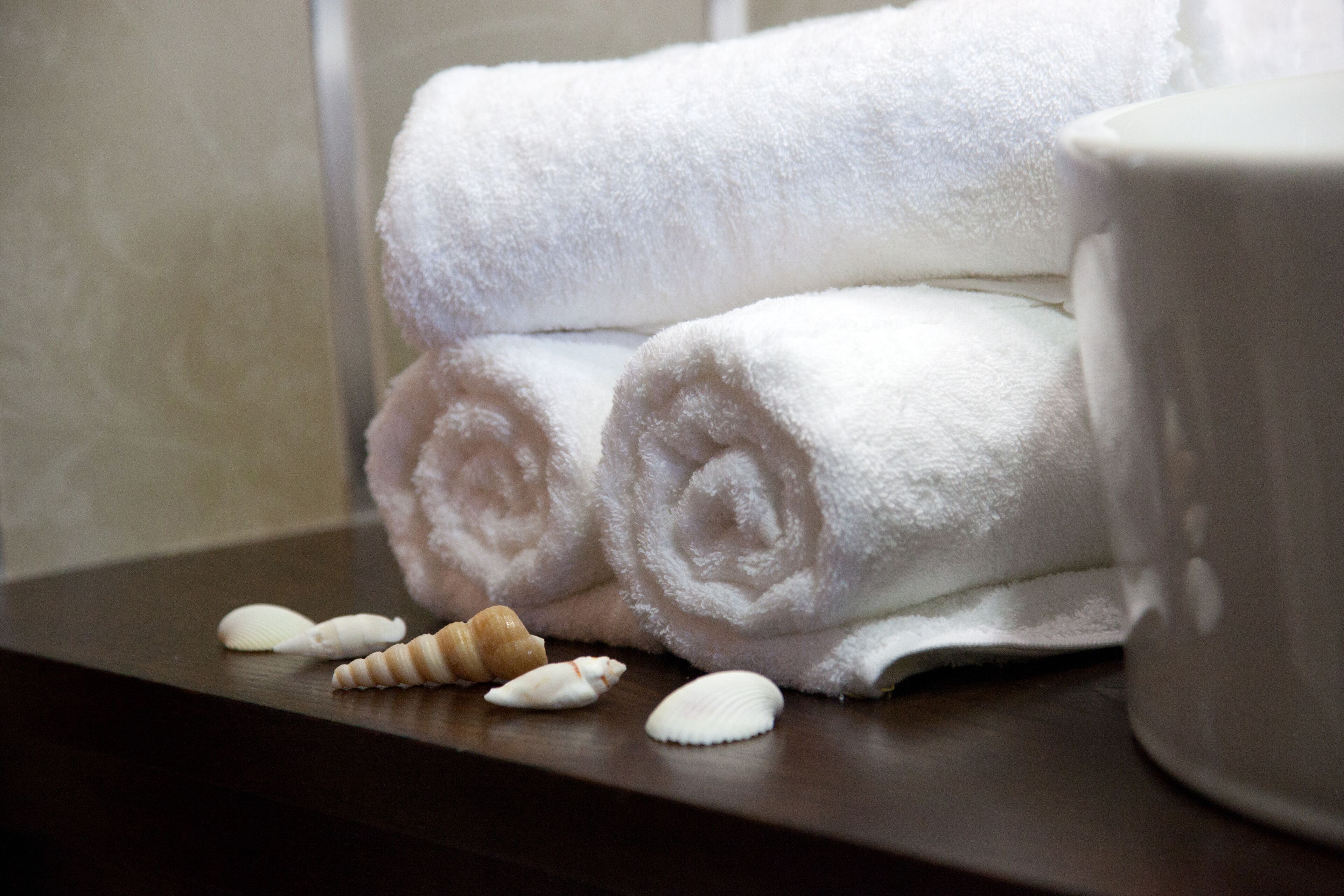 A stack of white towels and a ceramic mug on a wooden surface.