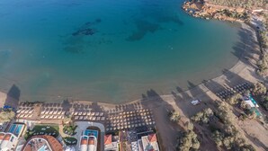 An aerial view of a coastal resort with a beach, pool area, and multiple buildings. - Golden Bay Suites (Chania)