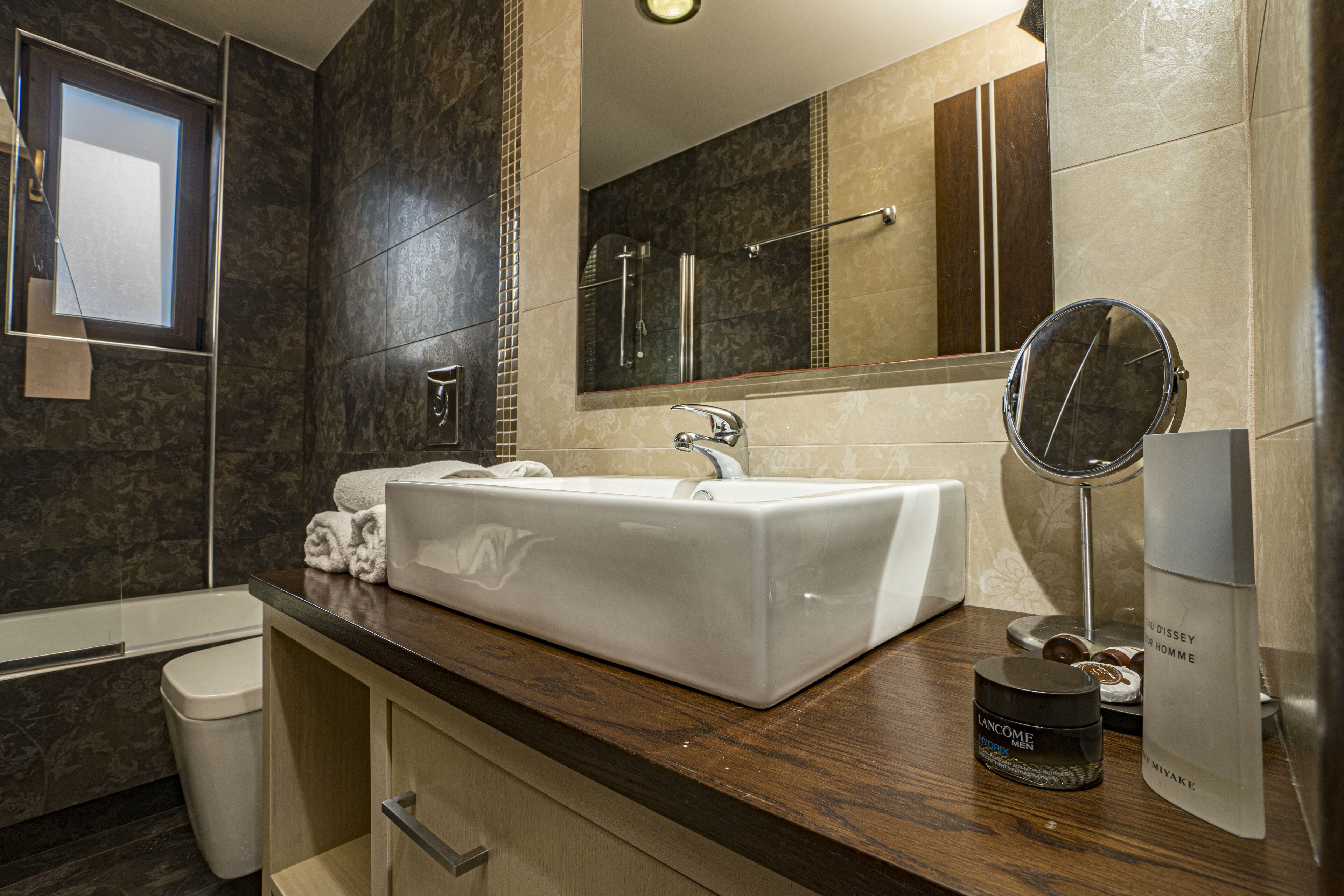 Un baño moderno con un lavamanos grande de color blanco, un espejo y una ducha.