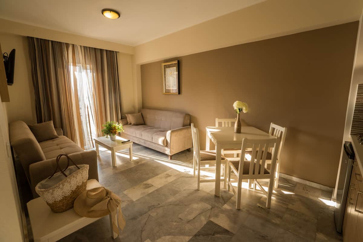 A living room with a sofa, a dining table with chairs, a coffee table, and a TV mounted on the wall.