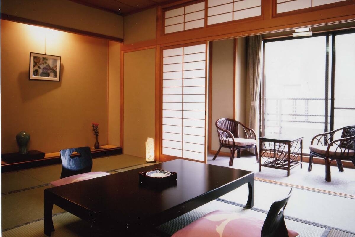 Une pièce de style japonais traditionnel, avec un sol recouvert de tatamis, une table basse et des portes coulissantes en papier de riz (shoji).
