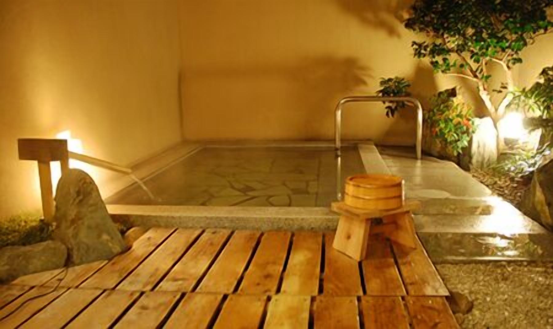 A traditional Japanese onsen with a wooden bench and a stone basin.