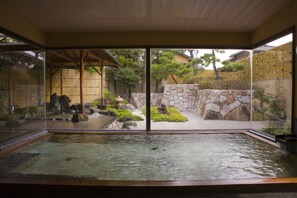 A traditional Japanese garden with a koi pond, bamboo structures, and a stone wall. - Hananoyado Nishikien (Mimasaka)