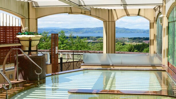 An indoor swimming pool with a view of mountains and a lake. - Hotel Listel Inawashiro Main (Inawashiro)