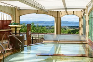 An indoor swimming pool with a view of mountains and a lake.