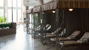 A spa area with sun loungers under a striped awning, a tiled floor, and a view of the outdoors. - Hotel Listel Inawashiro Main (Inawashiro)