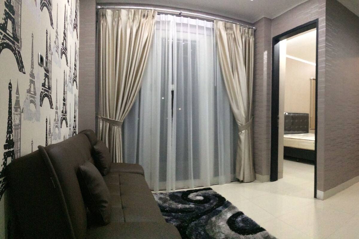 Une chambre d  ’hôtel moderne avec un canapé incurvé, une table en verre et un lit doté d’une tête de lit.