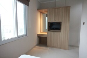 A bedroom with a bed, a desk, a TV, and a wardrobe. - Harvia Suites (Jakarta)