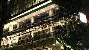 Un immeuble à plusieurs étages doté d’une façade en verre, d’un espace extérieur aménagé pour s’asseoir et d’un escalier.