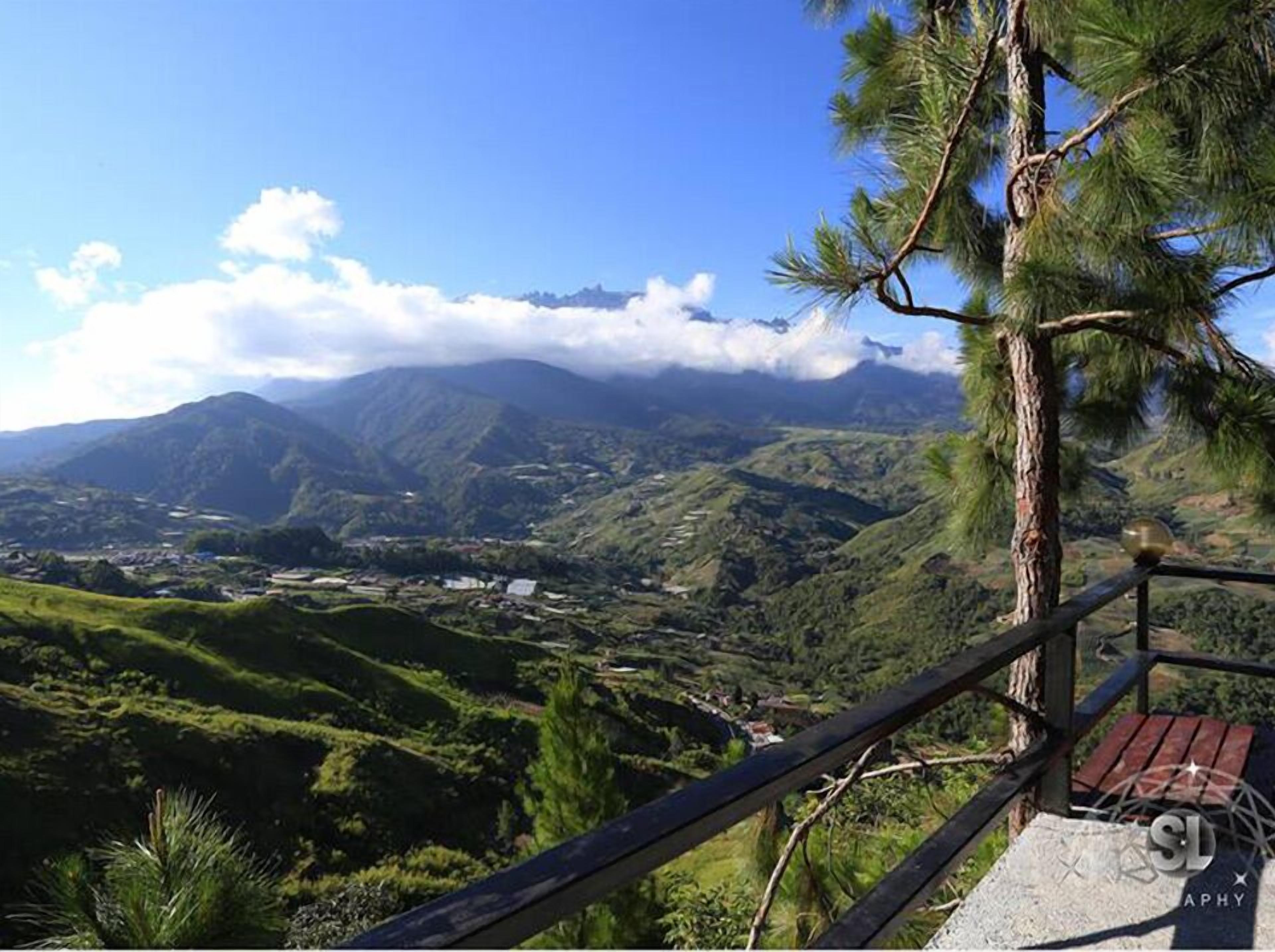 A scenic view from a wooden observation deck overlooking a valley with mountains in the background.